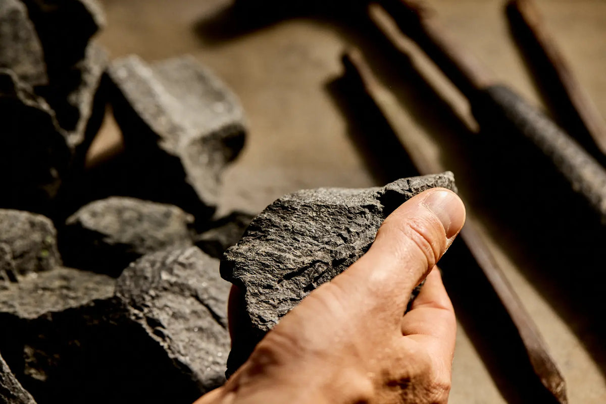 Hand des Steinmetzes prüft einen Slow Steam Stone über dem Werkzeug